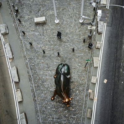 Pedestrians walk near the "Charging Bull" statue of Wall Street on March 12, 2020. in New York City. The Dow Jones industrial average fell 2,352.60 points, a decrease of almost 10% and the largest since 1987.