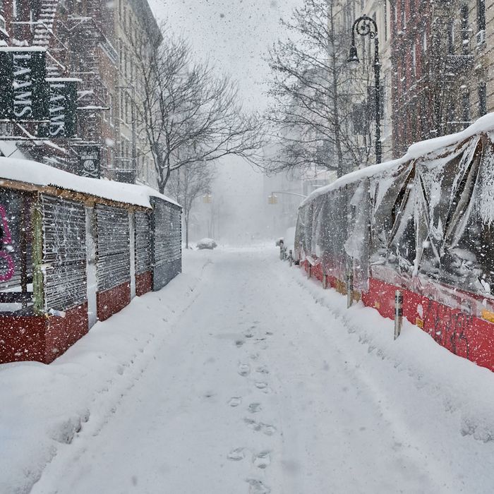 A snowy New York City street lined with snow-covered streeteries