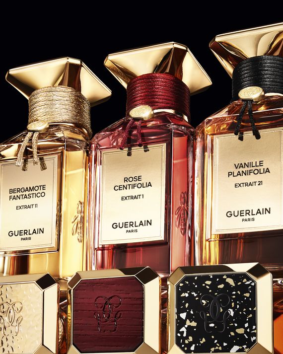 Three Guerlain perfume bottles lined up in a row with three limited-edition, colorful plate examples below.