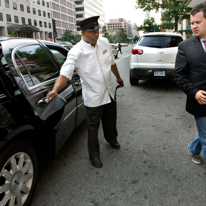 WASHINGTON, DC - JULY 16: (L-R) Hotel employee Tedros Birat opens the Uber Car door for Brendan Kownacki who uses the UBER car via a smartphone app to get around town rather than cabs in Washington, DC on July 16, 2012. He pays a little more than cabs but says it's worth it. It's automatically billed to his credit card, tip included, and the quality of the cars and drivers leaves no surprises for him or his clients. (Photo by Linda Davidson / The Washington Post)