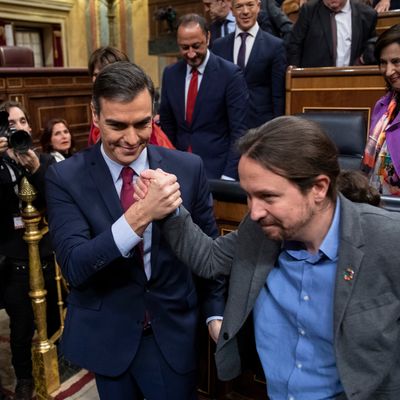 Spain's interim Prime Minister Pedro Sánchez (L) and Unidas Podemos party leader Pablo Iglesias (R) congratulate each other after learning the results of the vote on the last day of the investiture debate at the Spanish Parliament on January 07, 2020 in Madrid, Spain.