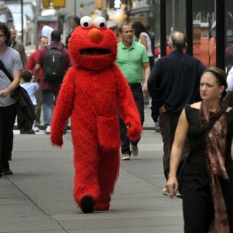 A person dressed as Elmo from the television show Sesame Street, walks to pose for pictures with tourists in Times Square October 4, 2012. GOP Presidential nominee Mitt Romney mentioned Sesame Street in Wednesday night's debate when he vowed to cut funding to public broadcasting if elected. PBS's Sesame Street will be celebrating its 43rd birthday this year. AFP PHOTO/ TIMOTHY A. CLARY (Photo credit should read TIMOTHY A. CLARY/AFP/Getty Images)