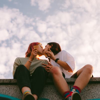 Lesbian couple kissing while sitting in the city during summer