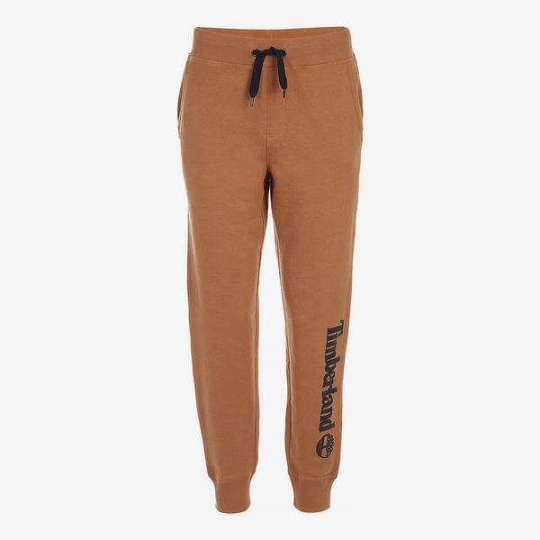 A pair of Timberland Big Boys Hemlock Wheat Logo-Print Joggers in a dark yellow-orange with a drawstring waist and a large black Timberland logo running down the left leg. The Strategist - 33 Things on Sale You’ll Actually Want to Buy: From Adidas to Le Creuset
