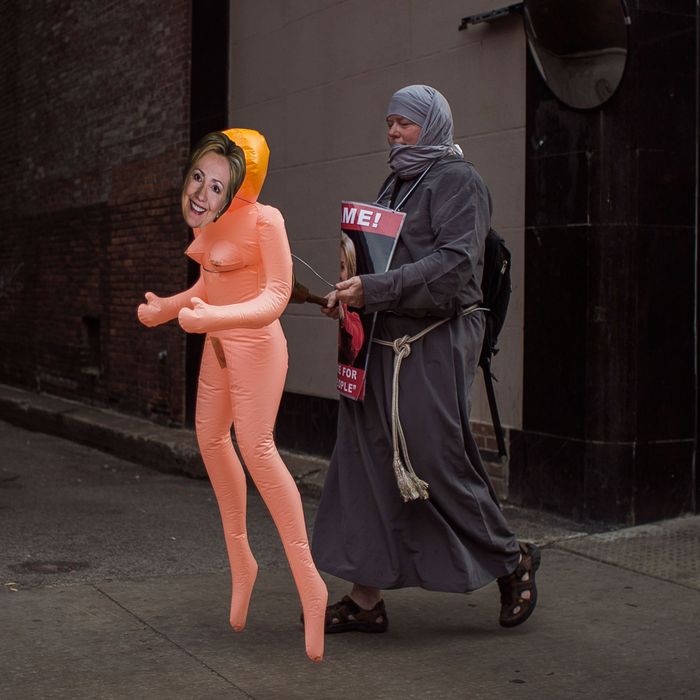 A man walks around the city holding Inflatable doll with Hillary Clinton's face mask on and a poster reading 