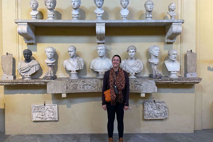 Maggie Slepian con ropa de Free Fly, posando junto a una pared de bustos en Roma.