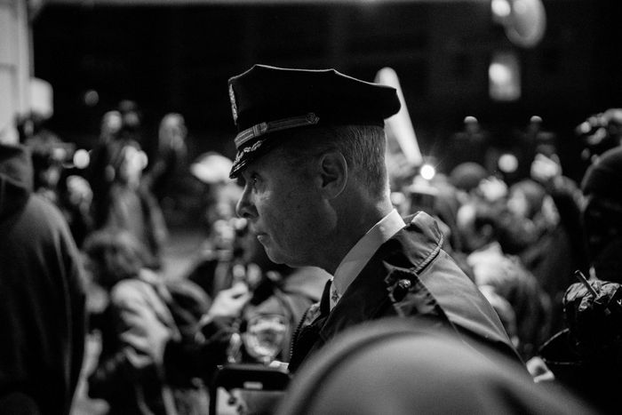 A white police officer stands, in profile, amid a crowd of demonstrators.