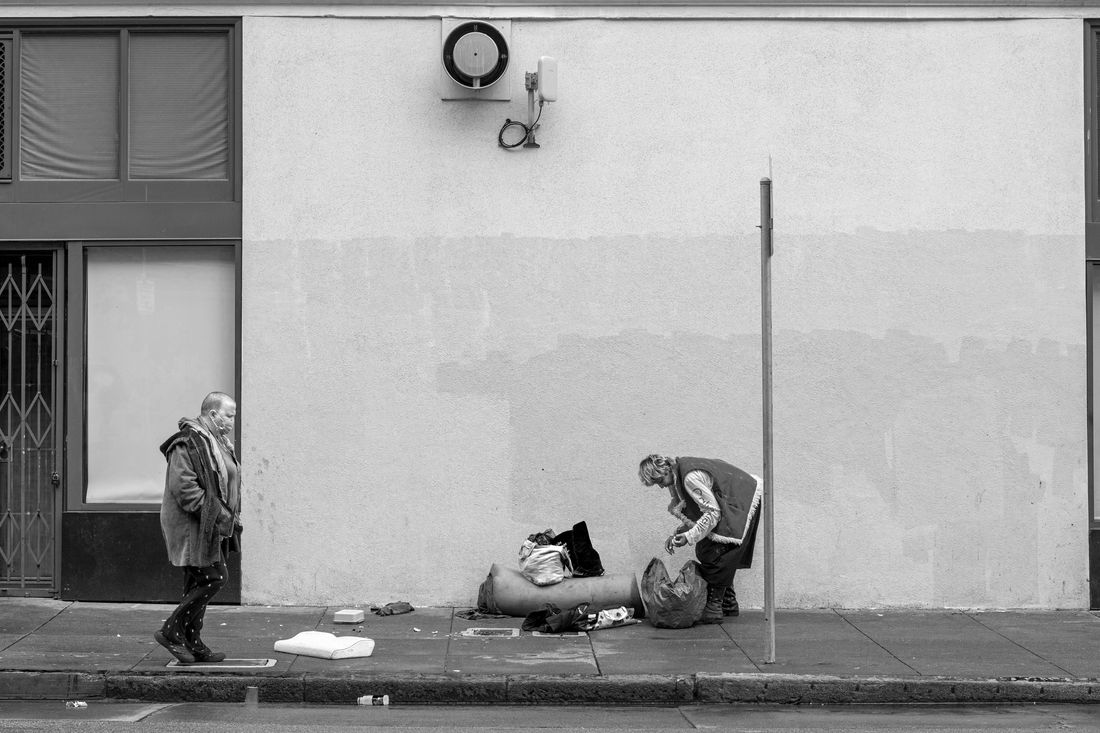 Knock-off luxury goods are displayed by sellers along a sidewalk