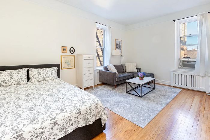A listing photo of a bedroom and couch in a studio in Brooklyn Heights