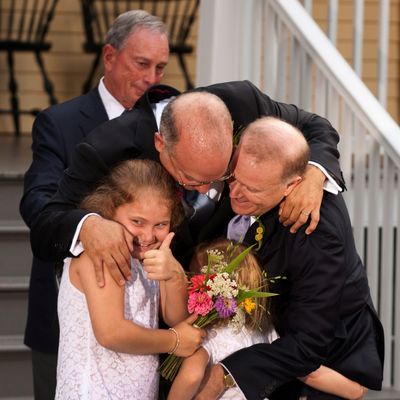 New York City Mayor Michael Bloomberg (back) watches while Jonathan Mintz (2nd L), the city's consumer affairs commissioner, John Feinblatt (R), a chief adviser to the mayor, along with their daughters Maeve (L) and Georgia do a group hug at Gracie Mansion in New York July 24, 2011. Hundreds of gay and lesbian New Yorkers were married this weekend, as the Empire State becomes the sixth state in the U.S. to embrace same-sex marriage. 
