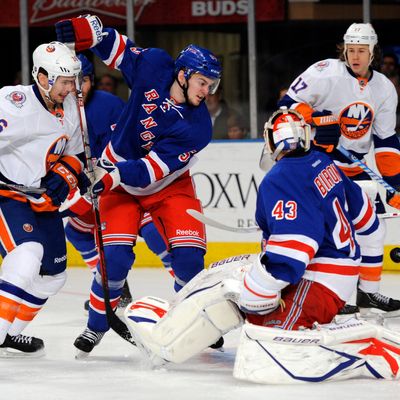 New York Rangers goalie Martin Biron, right, reaches back to make a save on a shot by New York Islanders' Tim Wallace (36) while Rangers' Tim Erixon (53) defends in the first period of an NHL hockey game in New York, Thursday, Dec. 22, 2011.