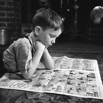 Boy reading funnies, indoors. 