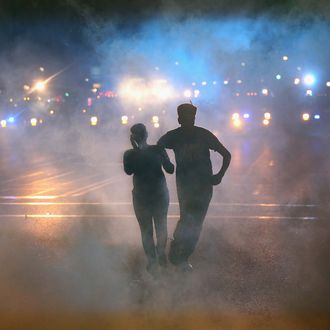 FERGUSON, MO - AUGUST 17: A woman is helped from the street after becoming overcome by tear gas during a demonstration over the killing of teenager Michael Brown by a Ferguson police officer on August 17, 2014 in Ferguson, Missouri. Despite the Brown family's continued call for peaceful demonstrations, violent protests have erupted nearly every night in Ferguson since his August 9, death. (Photo by Scott Olson/Getty Images)