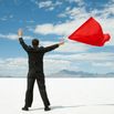 Businessman Waving Red Flag on Salt Flats.