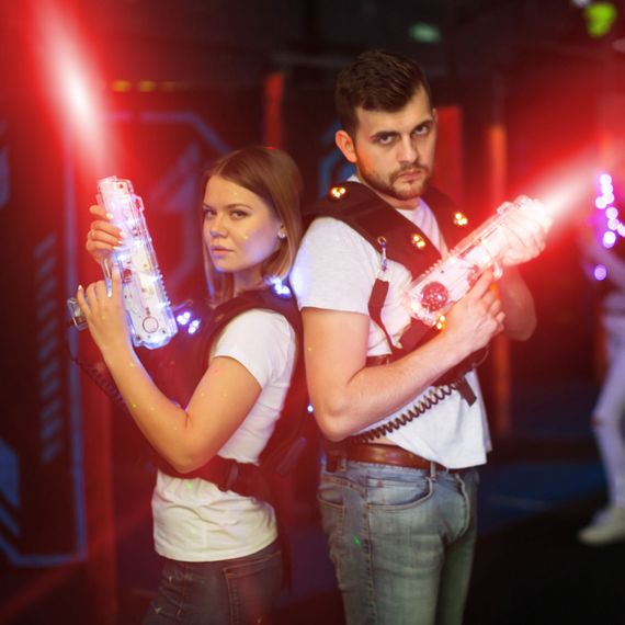 Two laser tag players standing back to back in bright beams