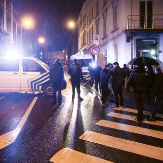 Journalists and residents stand near police vehicles as police set a large security perimeter in the city center of Verviers on January 15, 2015, during a 