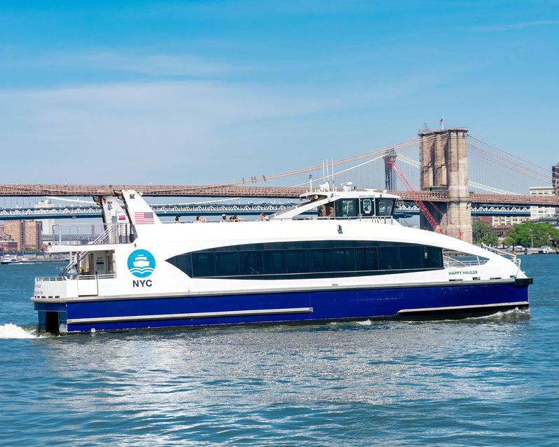 NYC Ferry service boat Happy Hauler on the route from Manhattan to Brooklyn. Historic Brooklyn Bridge in background - New York, USA - 2021