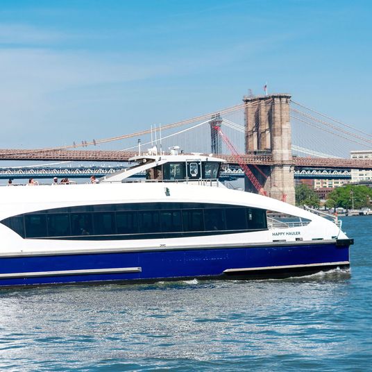 NYC Ferry service boat Happy Hauler on the route from Manhattan to Brooklyn. Historic Brooklyn Bridge in background - New York, USA - 2021