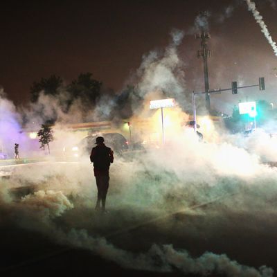 FERGUSON, MO - AUGUST 17: Tear gas fills the street as a demonstrator walks through the haze during protests over the killing of teenager Michael Brown by a Ferguson police officer, on August 17, 2014 in Ferguson, Missouri. Despite the Brown family's continued call for peaceful demonstrations, violent protests have erupted nearly every night in Ferguson since his August 9, death. (Photo by Scott Olson/Getty Images)