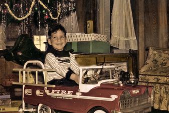 A little boy is in his new, toy fire engine Christmas morning.