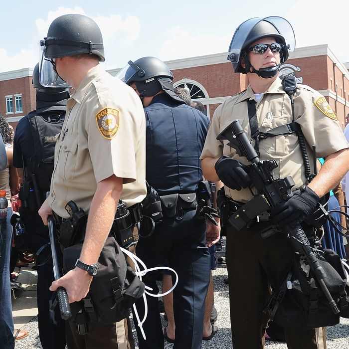 FERGUSON, MO - AUGUST 11: Armed St. Louis County Police Officers stand among citizens during a protest of the shooting death of 18-year-old Michael Brown by a Ferguson police officer, outside Ferguson Police Department Headquarters August 11, 2014 in Ferguson, Missouri. Civil unrest broke out as a result of the shooting of the unarmed black man as crowds looted and burned stores, vandalized vehicles and taunted police officers. Dozens were arrested for various infractions including assault, burglary and theft. (Photo by Michael B. Thomas/Getty Images)