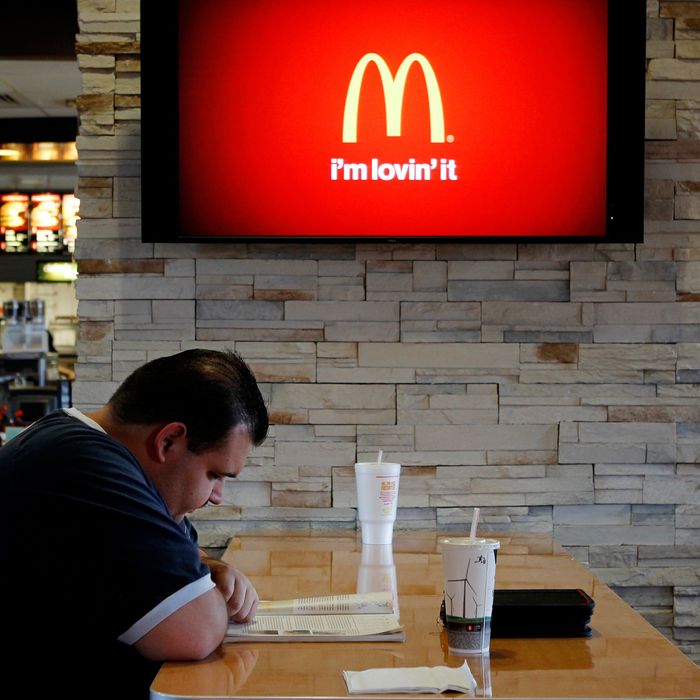 Customer Steven Price sits at a table near a HDTV screen showing the new McDonald's Channel featuring a commerical about McCafe drinks at a McDonald's restaurant, part of the test market for the channel in Norwalk, California October 17, 2011. McDonald's Corp will roll out its own family-friendly, all high-definition television channel to nearly 800 restaurants in Southern and Central California by March. The move is part of an expanded test of the service, which the world's biggest hamburger chain one day hopes to take across the United States. REUTERS/Fred Prouser (UNITED STATES - Tags: BUSINESS FOOD) --- Image by ? FRED PROUSER/Reuters/Corbis