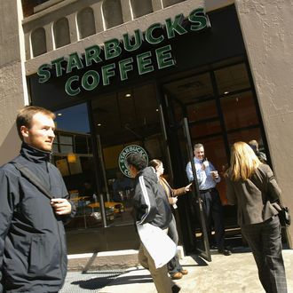 NEW YORK - OCTOBER 5: People walk past a Starbucks coffee shop October 5, 2004 in New York City. As coffee bean costs in the US have risen in the past two months, the Starbucks chain will add an average of 11 cents to the cost of a cup of coffee in its American outlets. (Photo by Spencer Platt/Getty Images)