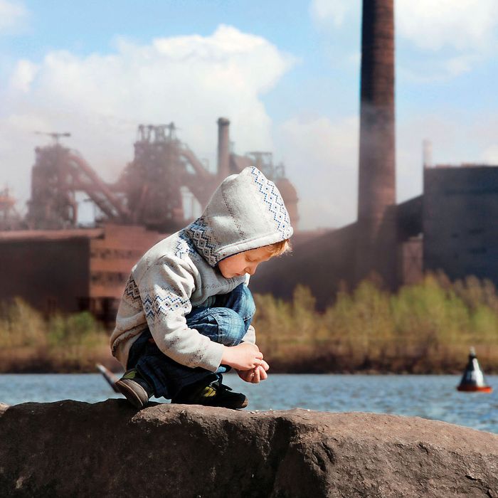 A child playing in front of a metallurgy factory.