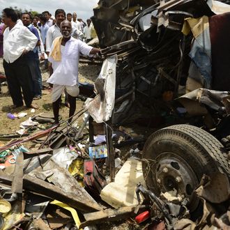 The mangled wreckage of a school bus is pictured as bystanders look on at the scene of the collision between a school bus and a train at Thoopran Mandal of Medak District, about 58 kilometers from Hyderabad, on July 24, 2014. A passenger train rammed into a school bus in southern India, killing at least 11 children, with fears the death toll could be as high as 25, officials said. 