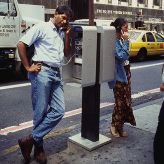 A man and woman using a telephone booth on the street in New York City, USA, 1995.