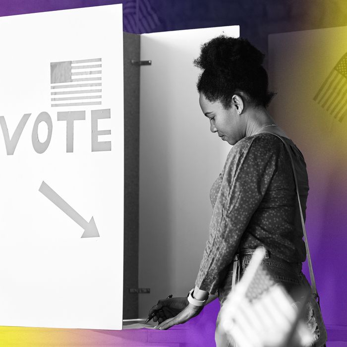 A black woman stands at a voting booth.