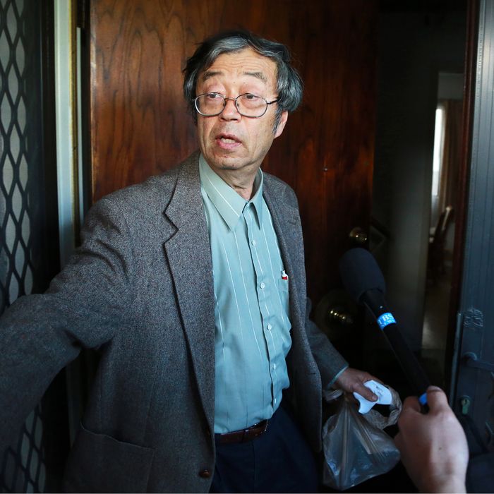Dorian S. Nakamoto, identified by Newsweek magazine as the founder of Bitcoin, stands surrounded by members of the media as he arrives home in Temple City, California, U.S., on Thursday, March 6, 2014. Nakamoto, a 64-year-old physicist, denied involvement in the digital currency before leading reporters on a multi-vehicle car chase and entering an Associated Press bureau. 