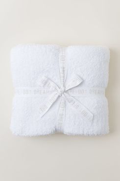 Barefoot Dreams CozyChic throw blanket in white, folded and tied with a branded ribbon