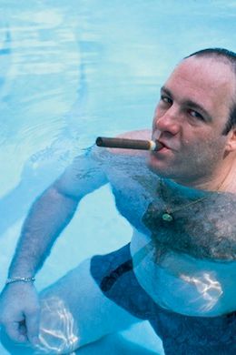 James Gandolfini, as Tony Soprano, smokes a cigar while standing in pool in a 1999 publicity still for the The Sopranos.