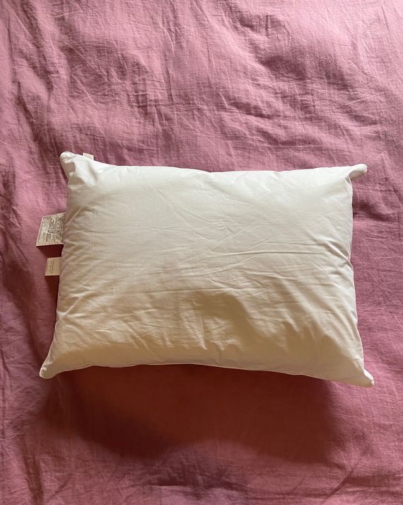 A white pillow on a pink duvet.