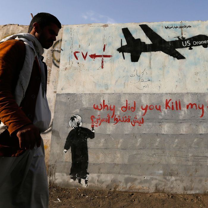 Man walks past a graffiti, denouncing strikes by U.S. drones in Yemen, painted on a wall in Sanaa
