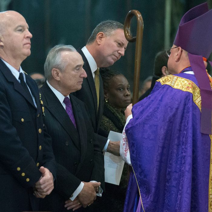 From left, NYPD's Chief of Department James O'Neill, NYPD Commissioner Bill Bratton, New York City Mayor Bill de Blasio, and New York City first lady Chirlane McCray greet Cardinal Timothy Dolan as they attend Mass at St. Patrick's Cathedral, Sunday, Dec. 21, 2014, in New York. An armed man walked up to two New York City police officers sitting inside a patrol car and opened fire Saturday afternoon, killing both before running into a nearby subway station and committing suicide, police said. (AP Photo/John Minchillo)