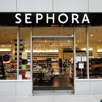 A man wearing a face mask walks past the Sephora logo and