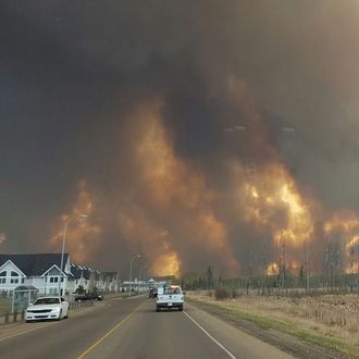 This photo take through a car windshield shows smoke rising from a wildfire rages outside of Fort McMurray, Alberta, Tuesday, May 3, 2016. The entire population of the Canadian oil sands city of Fort McMurray, has been ordered to evacuate as a wildfire whipped by winds engulfed homes and sent ash raining down on residents. (Mary Anne Sexsmith-Segato/The Canadian Press via AP) MANDATORY CREDIT