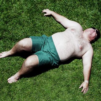 Large man lying on grass, wearing shorts, elevated view