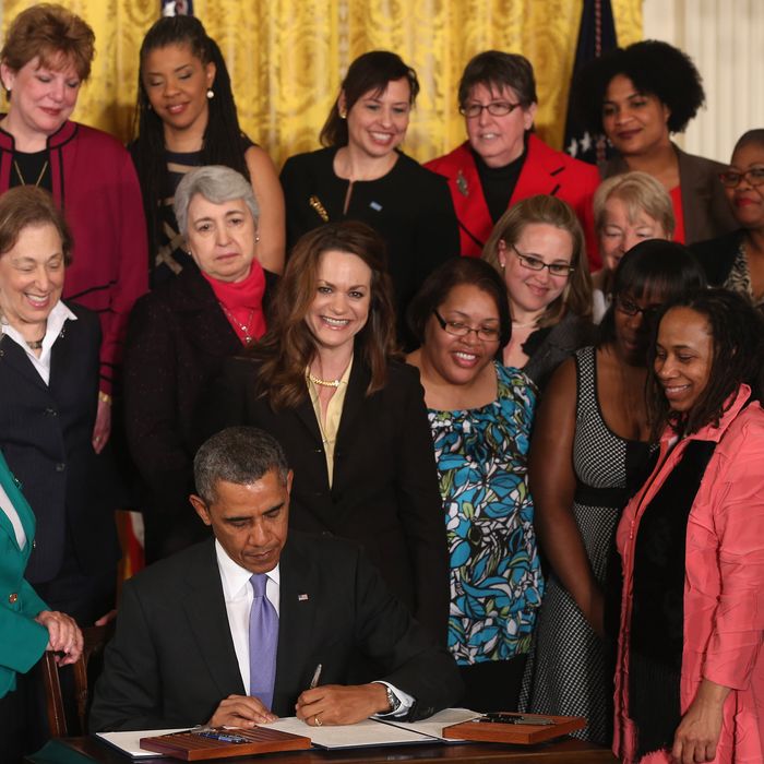 U.S. President Barack Obama is flanked by Lilly Ledbetter (L) and other women while signing an executive order banning federal contractors from retaliating against employees during an event in the East Room of the White House on April 8, 2014 in Washington, DC. President Obama announced that his administration will strengthen enforcement of equal pay laws for women. 
