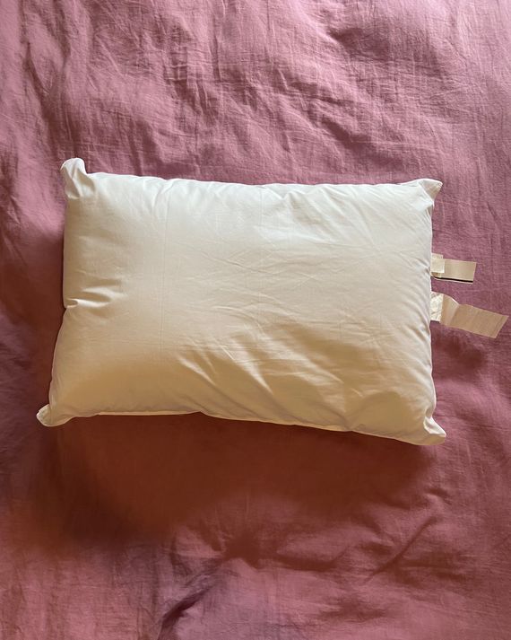 A white pillow on a pink duvet.