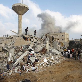 Smoke rises while Palestinian rescuers search for victims under the rubble of the home of the Duheir family, after it was destroyed by an Israeli air strike in Rafah on July 29, 2014, in the southern of Gaza strip. Bloodshed in war-torn Gaza surged with dozens more Palestinians killed as the conflict raged into a fourth week and Iran accused Israel of genocide in the tiny enclave. AFP PHOTO/ SAID KHATIB (Photo credit should read SAID KHATIB/AFP/Getty Images)