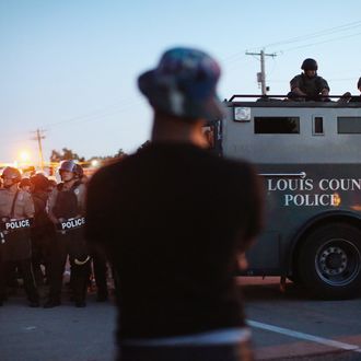 FERGUSON, MO - AUGUST 13: Police stand watch as demonstrators protest the shooting death of teenager Michael Brown on August 13, 2014 in Ferguson, Missouri. Brown was shot and killed by a Ferguson police officer on Saturday. Ferguson, a St. Louis suburb, is experiencing its fourth day of violent protests since the killing. (Photo by Scott Olson/Getty Images)