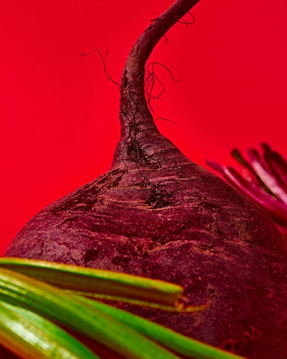 An ultra close-up of a raw beet against a red background