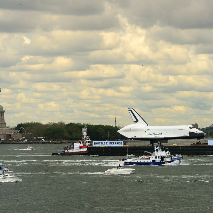 The space shuttle Enterprise is towed atop a barge going by the Statue of Liberty as it is viewed from the Staten Island ferry in New York, June 6, 2012. Enterprise was moved by barge to the Intrepid Sea, Air and Space Museum in New York where it will be permanently displayed. 