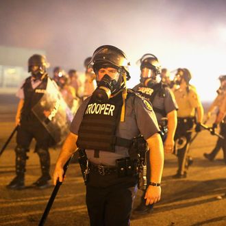 FERGUSON, MO - AUGUST 17: Police advance through a cloud of tear gas toward demonstrators protesting the killing of teenager Michael Brown on August 17, 2014 in Ferguson, Missouri. Police shot smoke and tear gas into the crowd of several hundred as they advanced near the police command center which has been set up in a shopping mall parking lot. Brown was shot and killed by a Ferguson police officer on August 9. Despite the Brown family's continued call for peaceful demonstrations, violent protests have erupted nearly every night in Ferguson since his death. (Photo by Scott Olson/Getty Images)