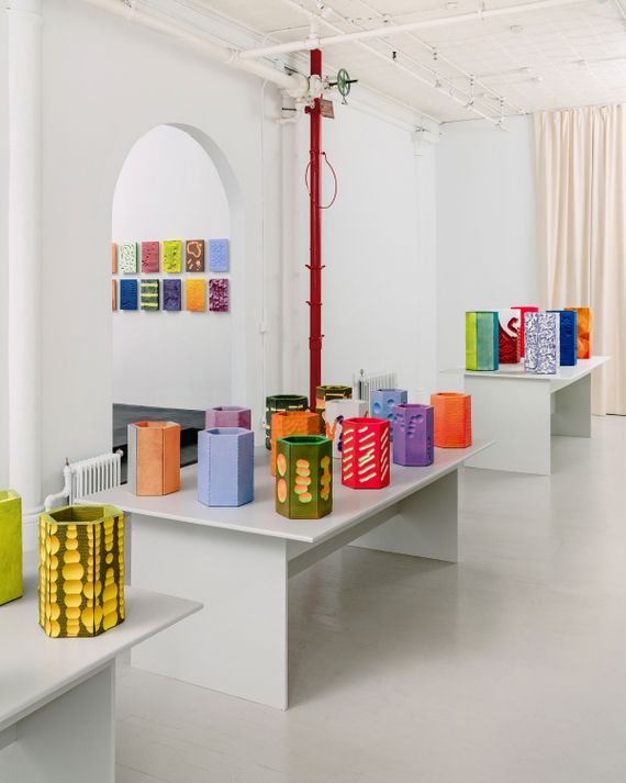 A white-wall gallery is filled with neon-colored vases of assorted sizes and textures.