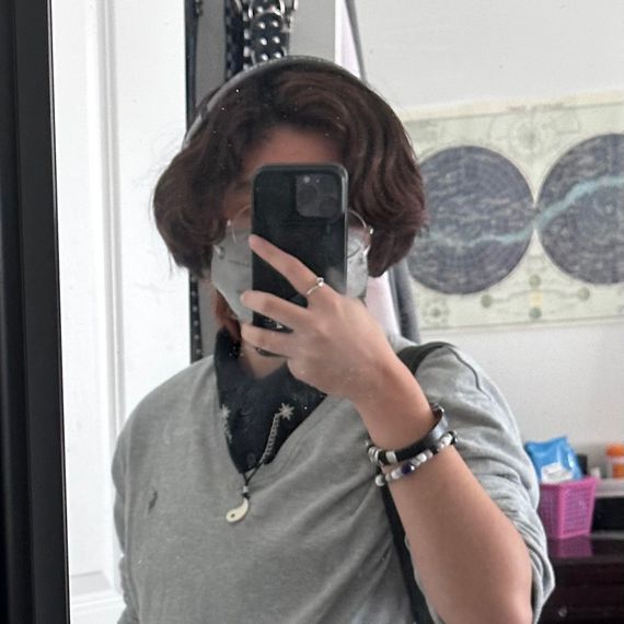A teenager with short, bobbed black hair and glasses wears a mask in this mirror selfie.