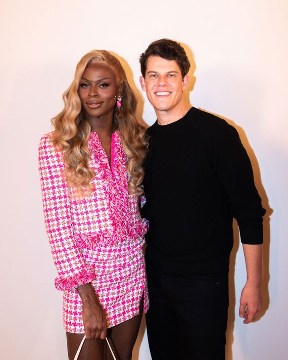 Simone is wearing a pink suit top and skirt, standing next to Wes Gordon, who is dressed in all black.